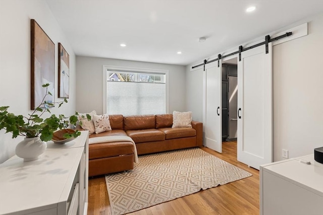 living room featuring a barn door, recessed lighting, and light wood-type flooring