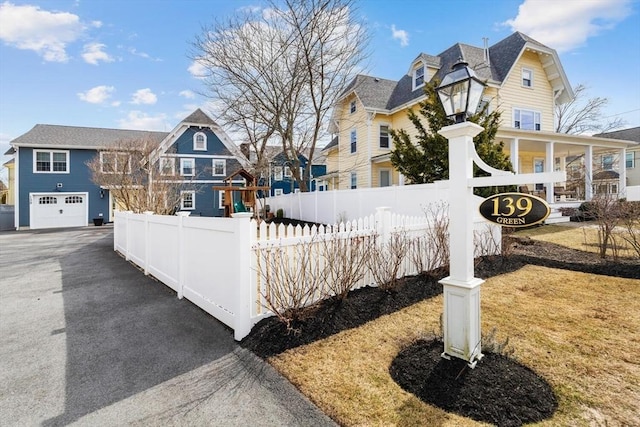 exterior space with driveway, a garage, a residential view, and a fenced front yard