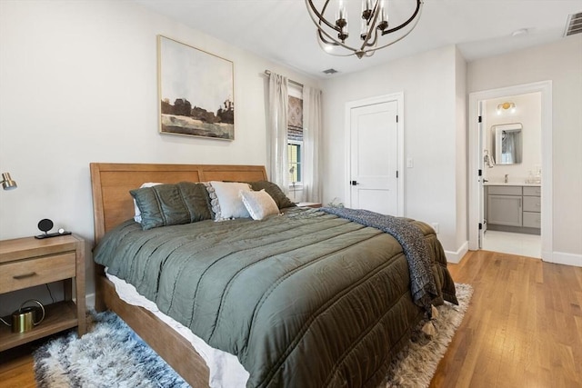 bedroom featuring light wood-type flooring, visible vents, ensuite bath, baseboards, and a chandelier