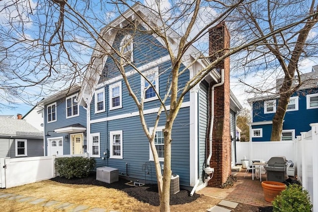 rear view of house featuring fence private yard, a chimney, and a patio area