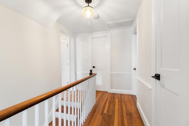 hallway with baseboards, an upstairs landing, visible vents, and light wood-type flooring