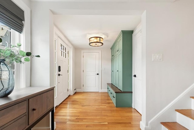 entryway with stairs, light wood-type flooring, and baseboards