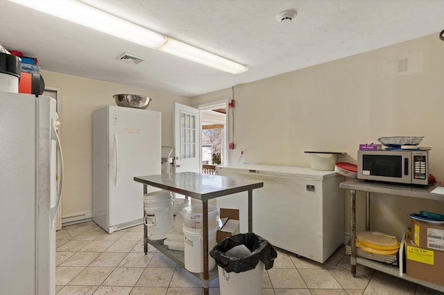 kitchen with white refrigerator, light tile floors, a baseboard heating unit, and fridge