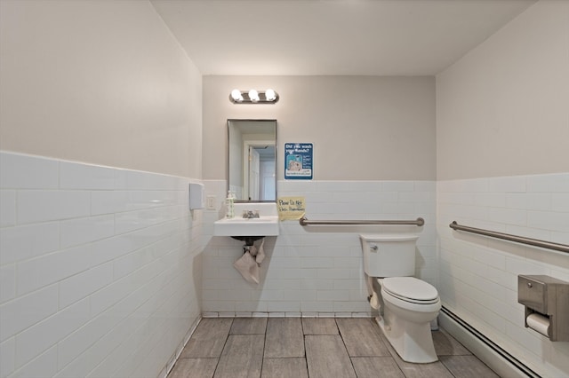 bathroom featuring tile walls, sink, toilet, and a baseboard heating unit