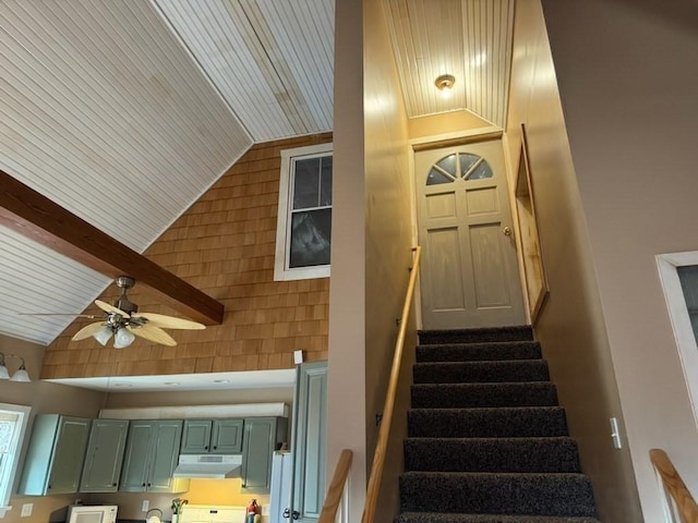 stairs with beam ceiling, high vaulted ceiling, ceiling fan, and wooden ceiling