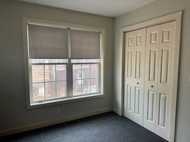 unfurnished bedroom featuring a closet and dark colored carpet