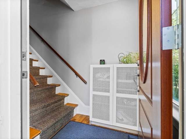 stairway featuring wood finished floors and a heating unit