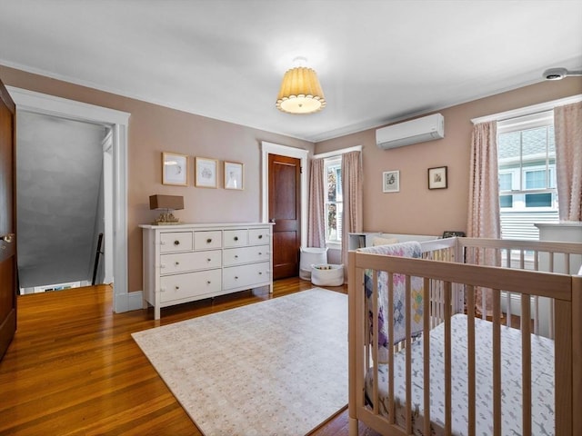 bedroom featuring a wall mounted AC, multiple windows, and wood finished floors