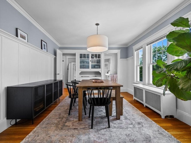 dining space with radiator heating unit, wood finished floors, and crown molding