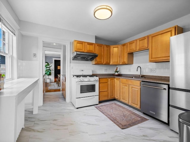 kitchen with stainless steel appliances, under cabinet range hood, a sink, and light marble finish floors