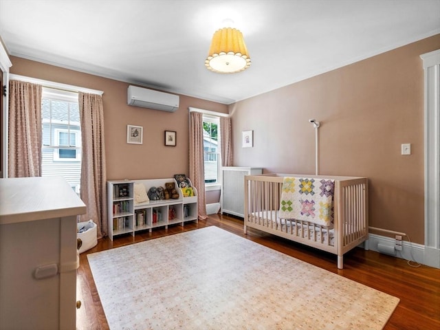 bedroom with a wall mounted AC, multiple windows, dark wood finished floors, and baseboards