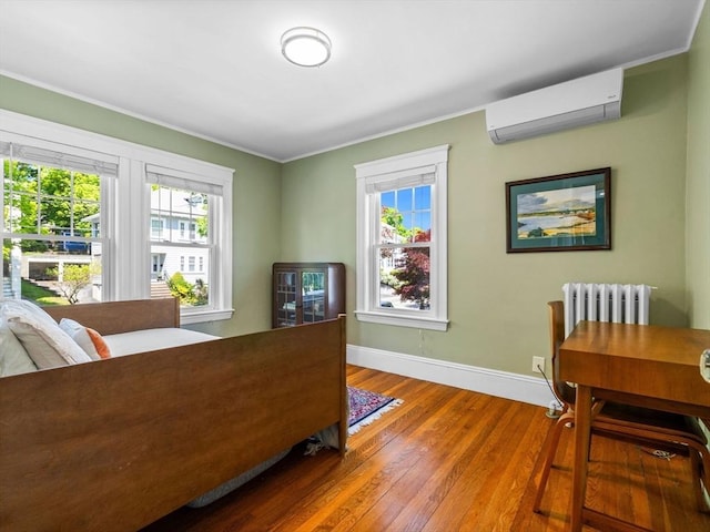 bedroom with a wall mounted AC, wood finished floors, baseboards, multiple windows, and ornamental molding