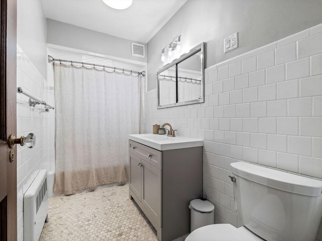 full bath featuring tile walls, toilet, vanity, shower / bath combo, and radiator