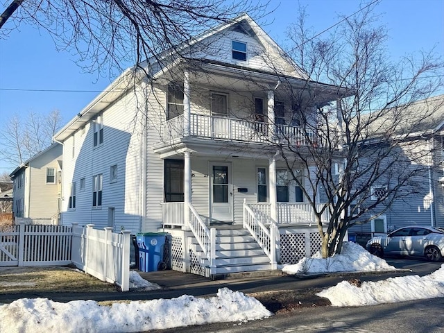 view of front of house with a porch, fence, and a balcony