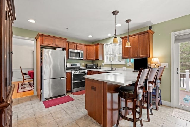 1 Cottonwood Cir, Kingston, NH 03848 - kitchen with appliances with stainless steel finishes, a peninsula, a sink, light countertops, and decorative light fixtures