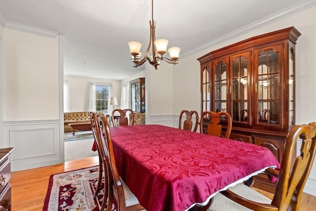 1 Cottonwood Cir, Kingston, NH 03848 - dining space with wood finished floors, a chandelier, a wainscoted wall, crown molding, and a decorative wall