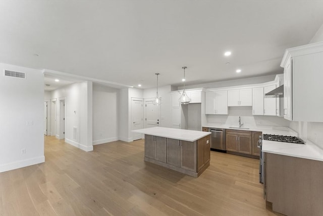 134 Court St Unit 2, Plymouth, MA 02360 - kitchen with wall chimney range hood, visible vents, a center island, a sink, and stainless steel appliances