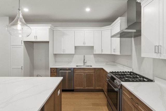 134 Court St Unit 2, Plymouth, MA 02360 - kitchen featuring white cabinets, light wood-style floors, wall chimney exhaust hood, appliances with stainless steel finishes, and a sink