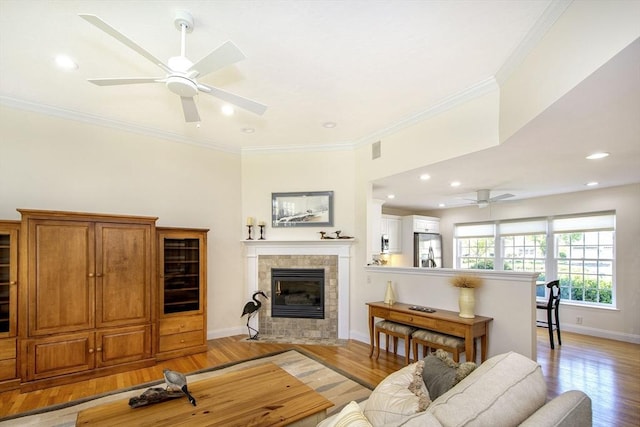 living area with light wood-style flooring, baseboards, and ornamental molding