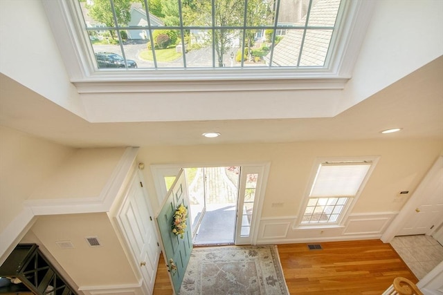 foyer entrance with a decorative wall, recessed lighting, wood finished floors, and a high ceiling