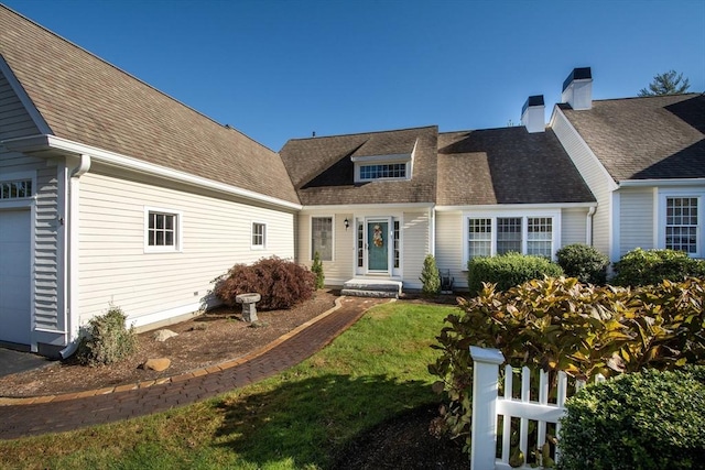 view of front of house featuring a front lawn, a garage, a chimney, and a shingled roof