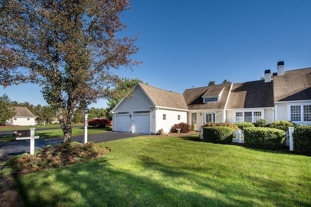 view of front of home featuring a garage, driveway, a shingled roof, and a front yard