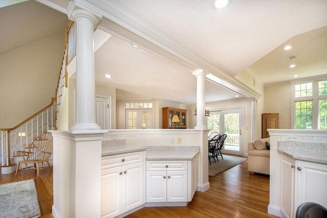 kitchen with light wood-type flooring, decorative columns, and open floor plan