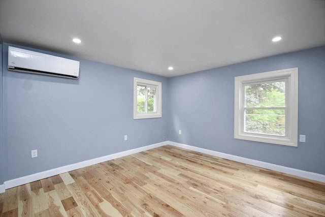empty room with recessed lighting, a wall unit AC, wood finished floors, and baseboards