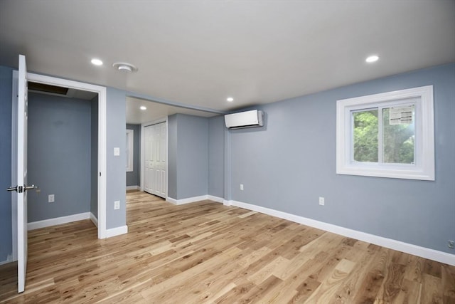 below grade area featuring baseboards, a wall mounted air conditioner, light wood finished floors, and recessed lighting
