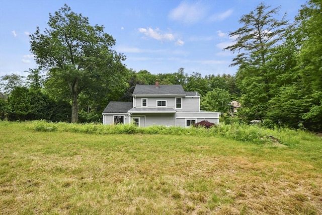 back of house with a wooded view and a chimney