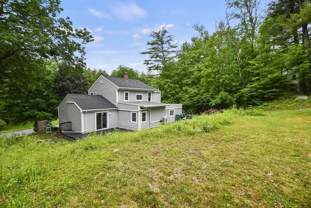 back of property with a deck, a shingled roof, and a chimney
