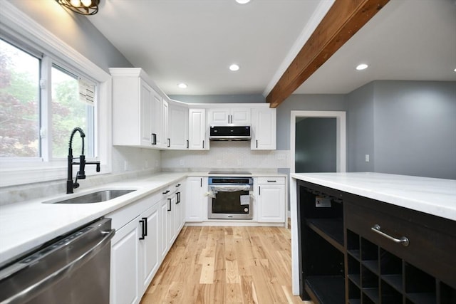 kitchen featuring decorative backsplash, appliances with stainless steel finishes, light countertops, white cabinets, and a sink