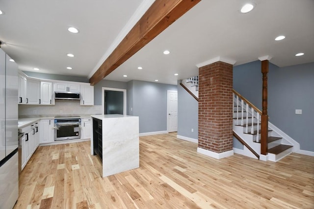 kitchen with light wood finished floors, baseboards, appliances with stainless steel finishes, and light countertops