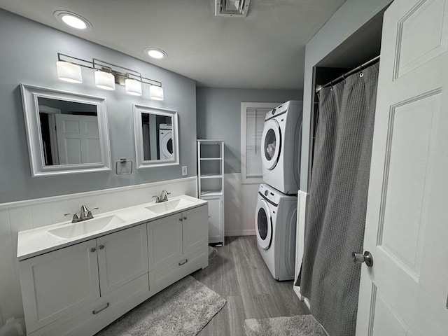 bathroom with vanity, hardwood / wood-style floors, and stacked washer and clothes dryer