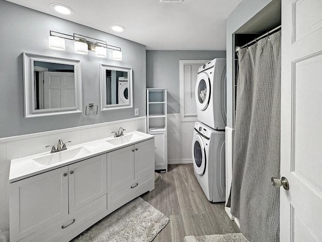 bathroom with hardwood / wood-style flooring, stacked washer and dryer, and vanity