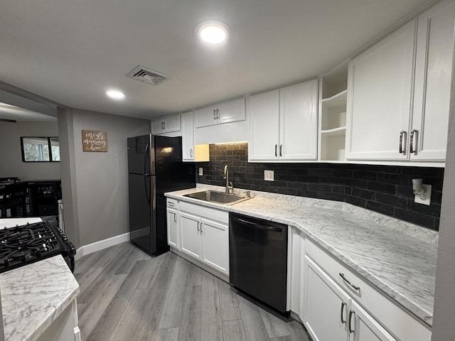 kitchen featuring sink, white cabinets, light stone counters, black appliances, and light hardwood / wood-style flooring