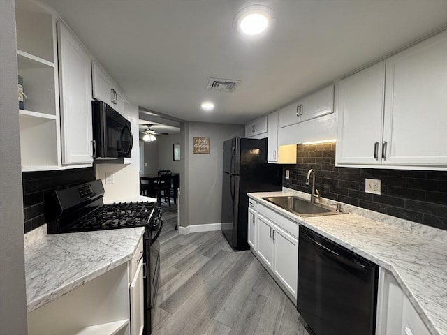 kitchen featuring light stone counters, sink, black appliances, and white cabinets