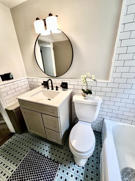 3 Rosewood Dr, Worcester, MA 01602 - bathroom featuring tile walls, a wainscoted wall, a bathtub, vanity, and tile patterned floors