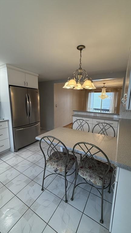 dining area featuring a chandelier and light marble finish floors