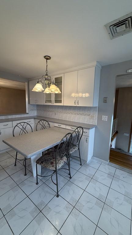 dining space with a chandelier and light marble finish flooring