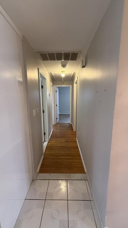 hallway featuring light marble finish floors and baseboards