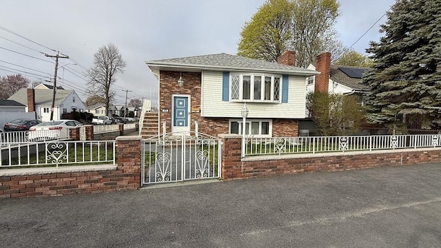 view of front facade featuring a fenced front yard, a chimney, brick siding, and a gate