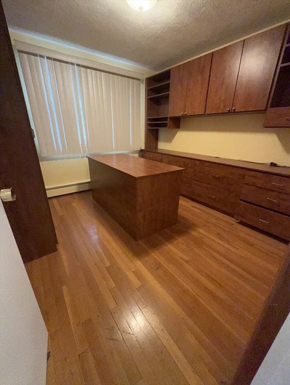 unfurnished office featuring baseboard heating, dark wood-style flooring, and a textured ceiling