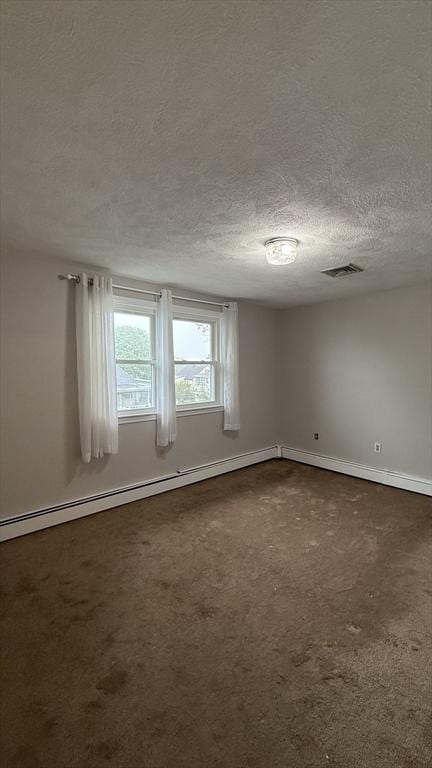 empty room featuring a textured ceiling, dark colored carpet, and baseboards