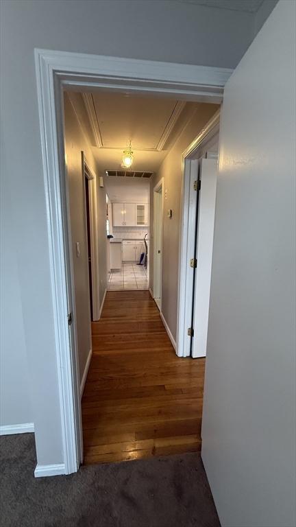 hallway with attic access, wood finished floors, and baseboards