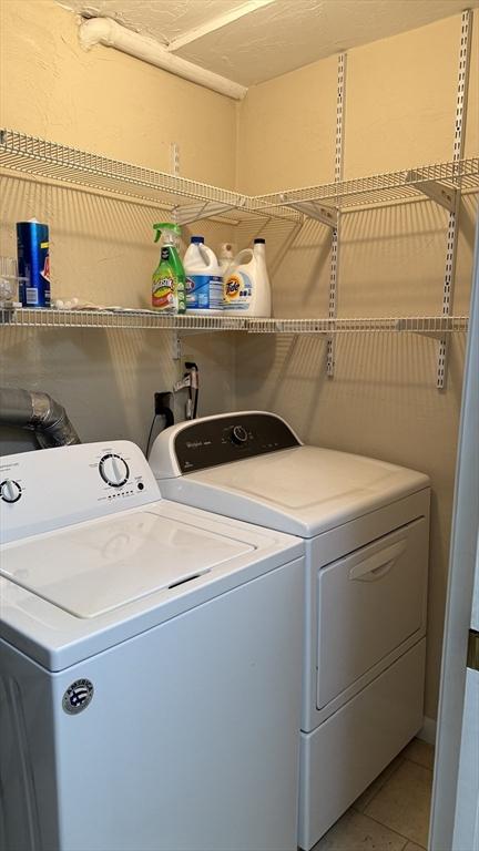 laundry area with washing machine and clothes dryer and light tile patterned flooring
