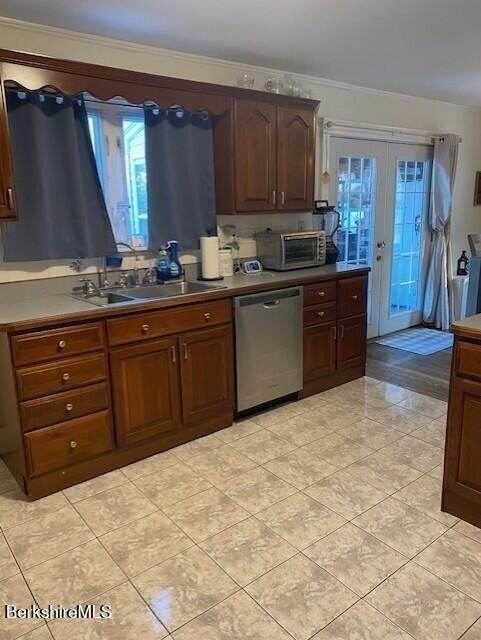 kitchen with french doors, sink, light tile patterned floors, ornamental molding, and dishwasher