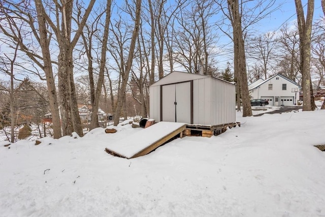 snow covered structure featuring a storage unit and an outdoor structure