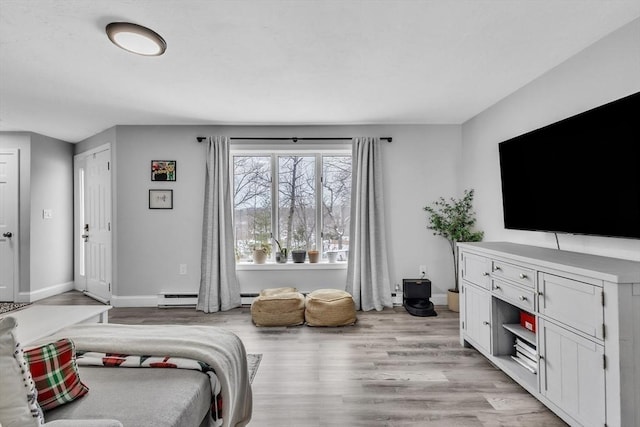 bedroom featuring a baseboard radiator, baseboards, and light wood-style flooring