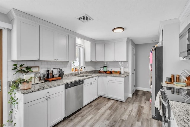 kitchen with light wood finished floors, visible vents, stainless steel appliances, white cabinetry, and a sink